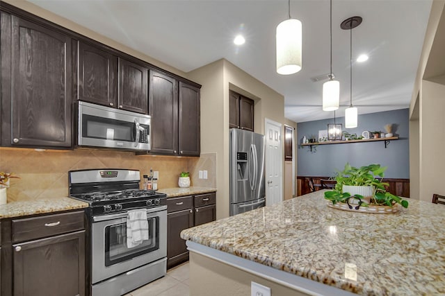 kitchen with light stone counters, dark brown cabinetry, appliances with stainless steel finishes, and hanging light fixtures