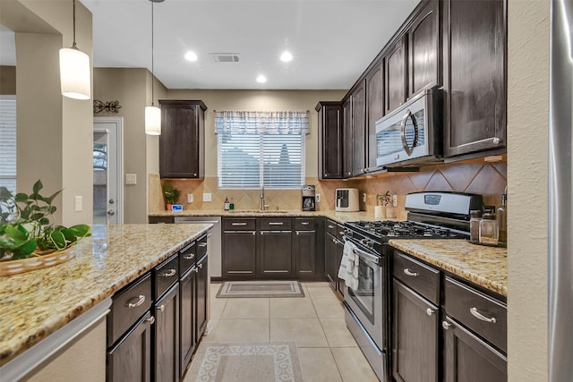 kitchen featuring stainless steel appliances, dark brown cabinets, light tile patterned floors, and decorative light fixtures