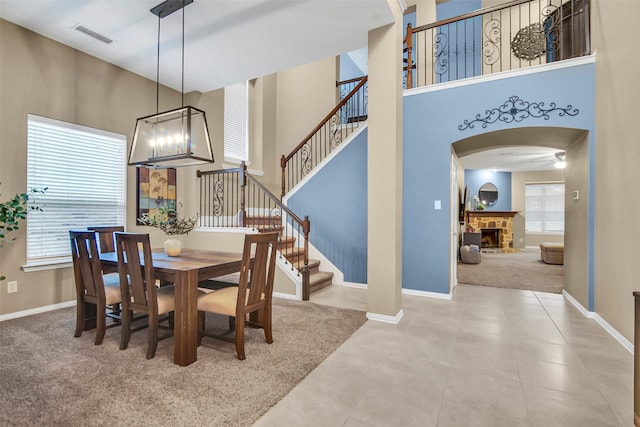 tiled dining room featuring a stone fireplace and a high ceiling