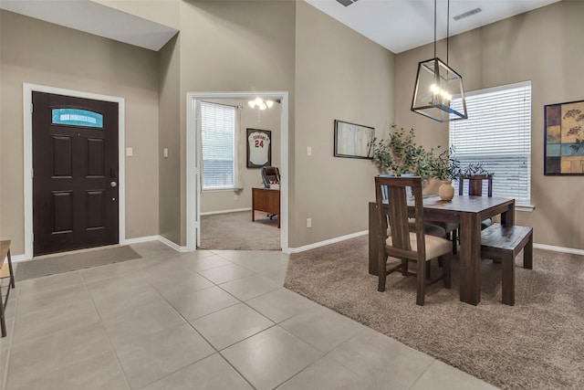 tiled dining space featuring a chandelier and a high ceiling