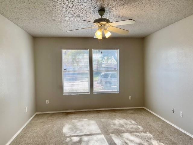 empty room featuring ceiling fan, light carpet, and a textured ceiling