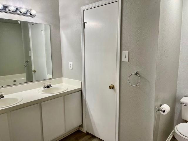 bathroom with toilet, hardwood / wood-style flooring, and vanity