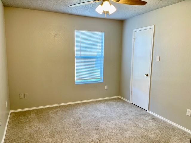 spare room with a textured ceiling, ceiling fan, and light carpet