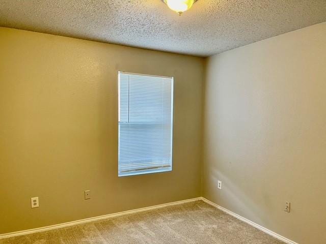 unfurnished room featuring a textured ceiling and light carpet