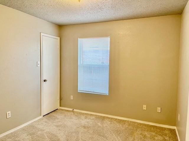 unfurnished room with a textured ceiling and light carpet