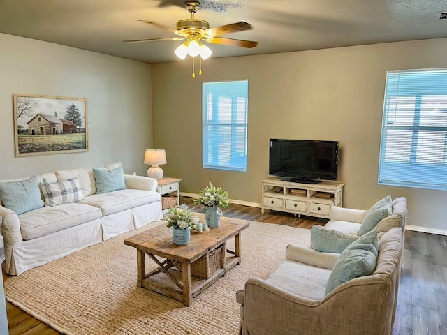 living room featuring ceiling fan, dark hardwood / wood-style floors, and plenty of natural light