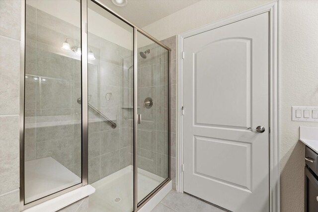 bathroom with an enclosed shower, vanity, and tile patterned flooring