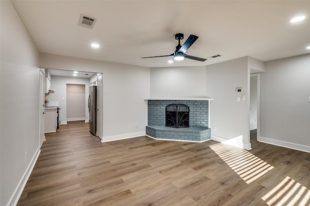 unfurnished living room featuring ceiling fan, hardwood / wood-style floors, and a fireplace