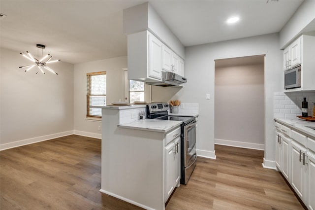 kitchen with kitchen peninsula, a chandelier, decorative backsplash, white cabinetry, and appliances with stainless steel finishes