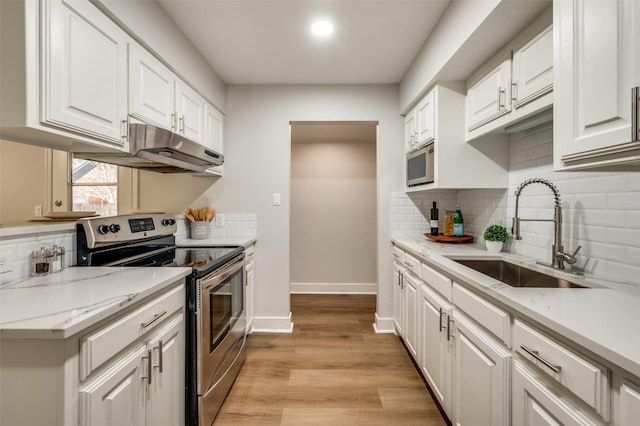 kitchen with sink, white cabinetry, light hardwood / wood-style floors, light stone countertops, and appliances with stainless steel finishes