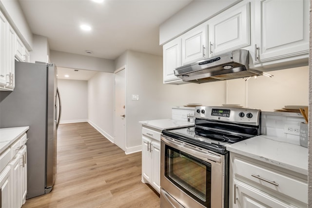 kitchen with light stone countertops, white cabinets, light hardwood / wood-style floors, and appliances with stainless steel finishes