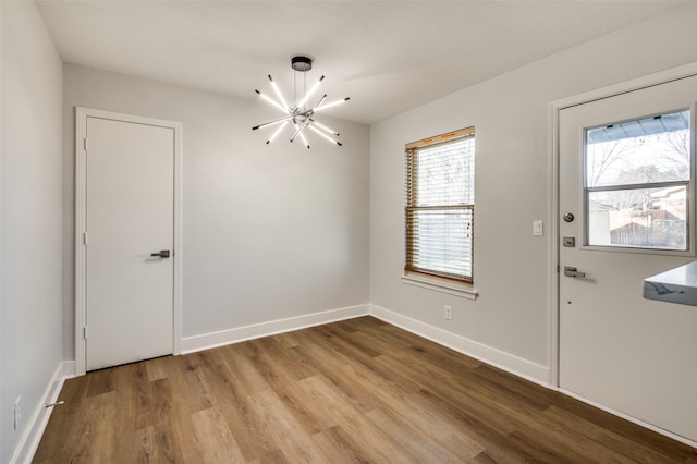 empty room with a notable chandelier and light hardwood / wood-style flooring