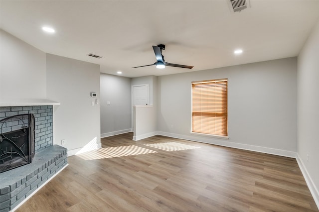 unfurnished living room featuring a brick fireplace, ceiling fan, and light hardwood / wood-style flooring