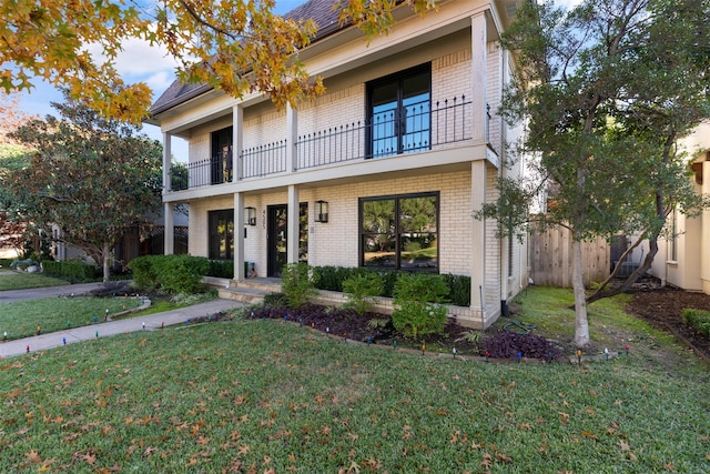 view of front of home featuring a balcony and a front lawn