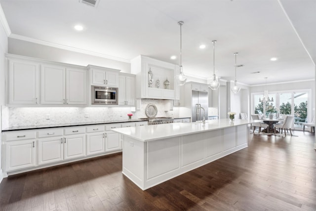 kitchen featuring built in appliances, decorative light fixtures, white cabinets, a spacious island, and decorative backsplash