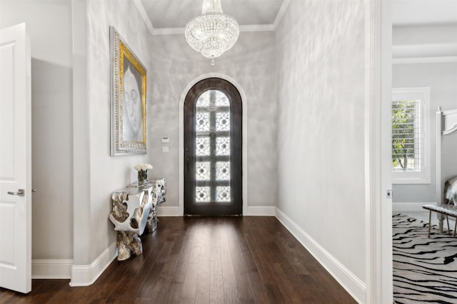 entryway with ornamental molding, dark wood-type flooring, and an inviting chandelier