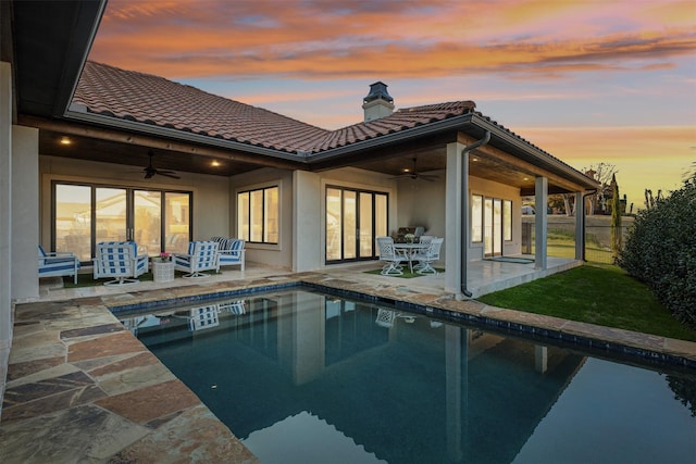 back house at dusk with ceiling fan, an outdoor hangout area, and a patio area