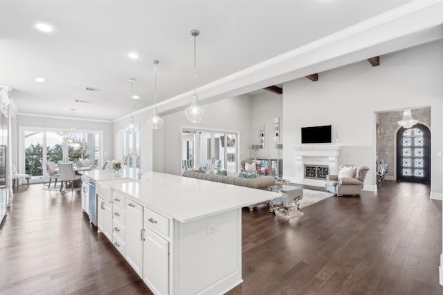 kitchen featuring dark hardwood / wood-style floors, decorative light fixtures, a notable chandelier, a kitchen island with sink, and white cabinetry