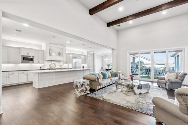 living room with sink, a high ceiling, beamed ceiling, and dark hardwood / wood-style floors