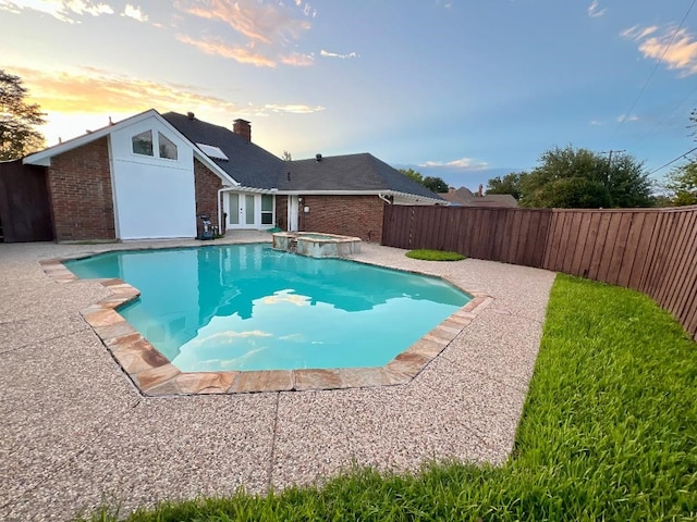 pool at dusk featuring an in ground hot tub