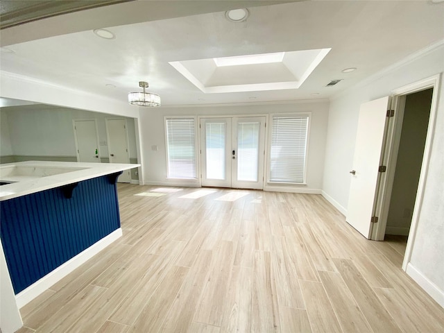 kitchen with french doors, a kitchen breakfast bar, ornamental molding, a tray ceiling, and a notable chandelier