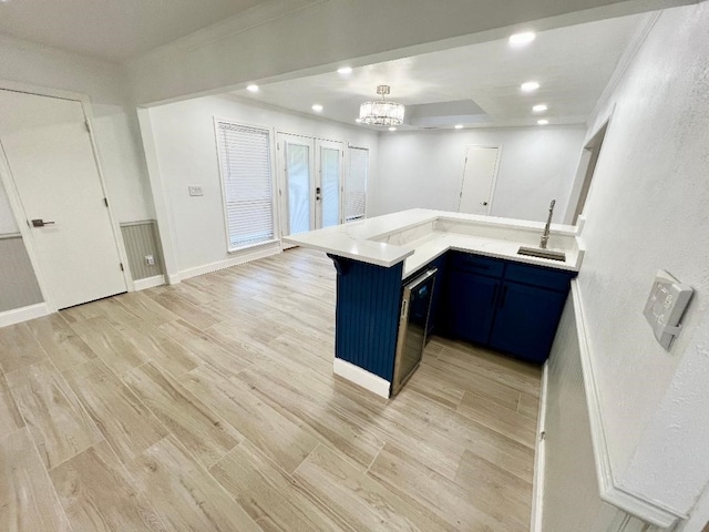 kitchen featuring kitchen peninsula, a breakfast bar, light wood-type flooring, blue cabinetry, and sink