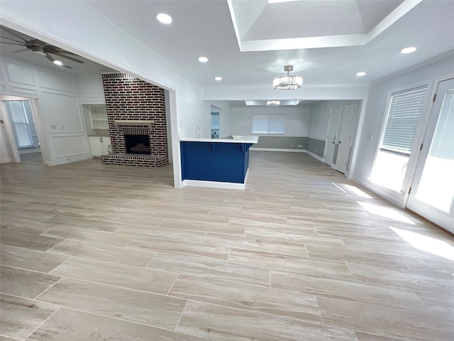 kitchen with ceiling fan with notable chandelier, a fireplace, ornamental molding, a kitchen breakfast bar, and sink