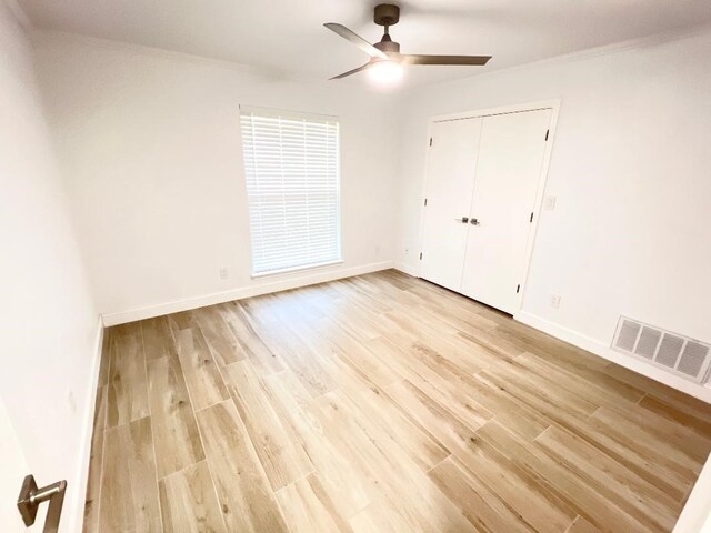 unfurnished bedroom with light wood-type flooring, ceiling fan, crown molding, and a closet