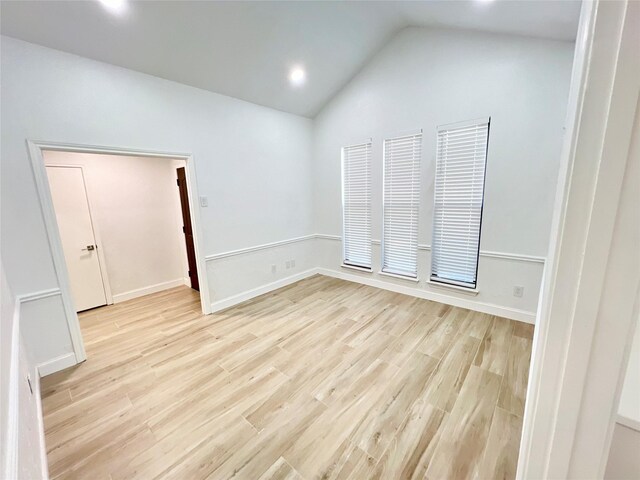 spare room featuring lofted ceiling and light wood-type flooring