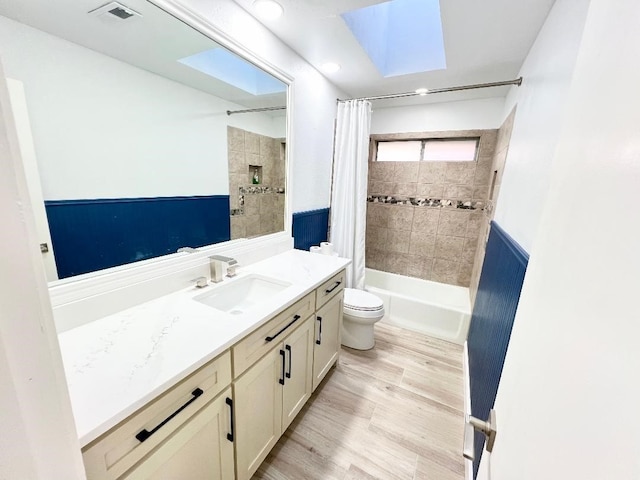 full bathroom featuring toilet, a skylight, shower / bathtub combination with curtain, wood-type flooring, and vanity