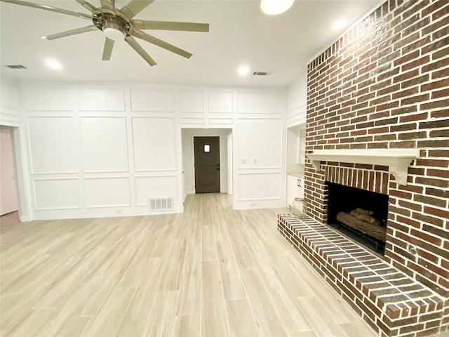 unfurnished living room with light hardwood / wood-style floors, ceiling fan, and a fireplace