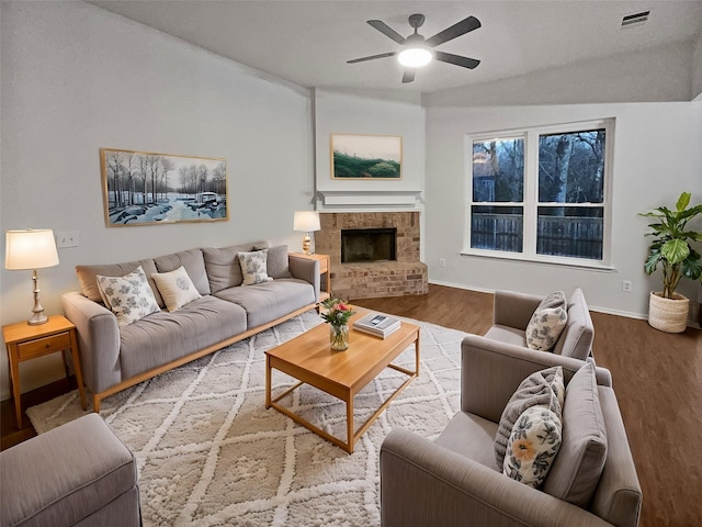 living room featuring ceiling fan, hardwood / wood-style floors, lofted ceiling, and a fireplace