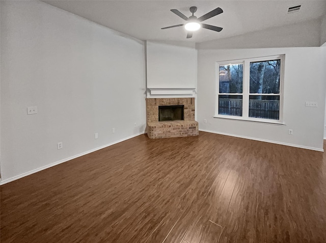 unfurnished living room with a brick fireplace, ceiling fan, vaulted ceiling, and dark hardwood / wood-style floors