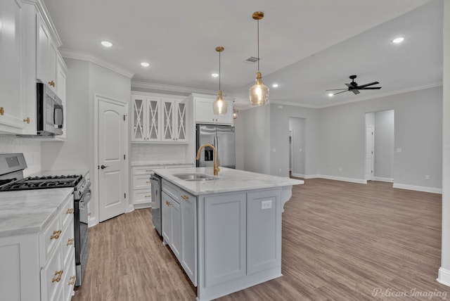 kitchen with stainless steel appliances, decorative backsplash, a kitchen island with sink, white cabinets, and sink