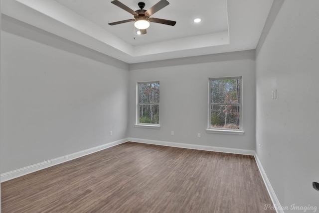 spare room featuring hardwood / wood-style flooring, ceiling fan, and a tray ceiling