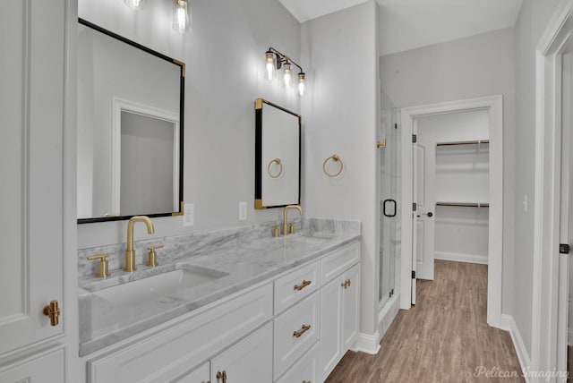 bathroom with an enclosed shower, vanity, and wood-type flooring