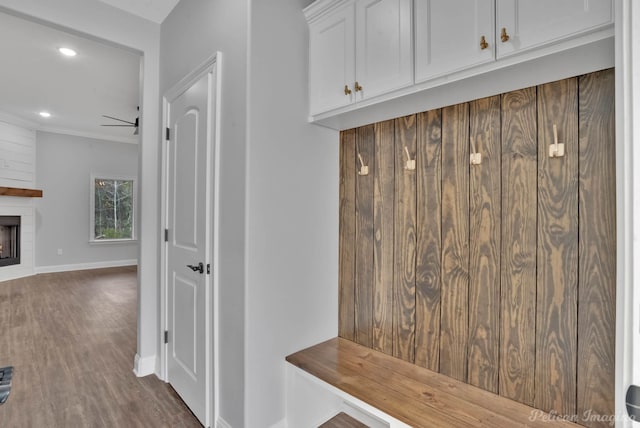 mudroom with a large fireplace, ceiling fan, dark hardwood / wood-style flooring, and ornamental molding