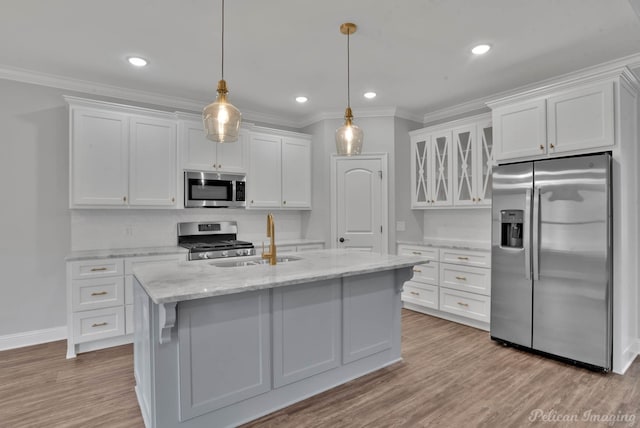 kitchen with light stone counters, stainless steel appliances, a center island with sink, white cabinetry, and sink