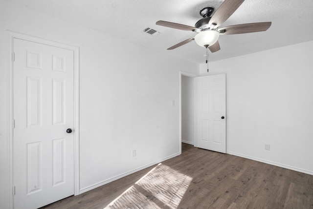 spare room with a textured ceiling, ceiling fan, and dark hardwood / wood-style flooring