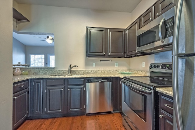 kitchen with stainless steel appliances, dark wood-type flooring, light stone countertops, and sink