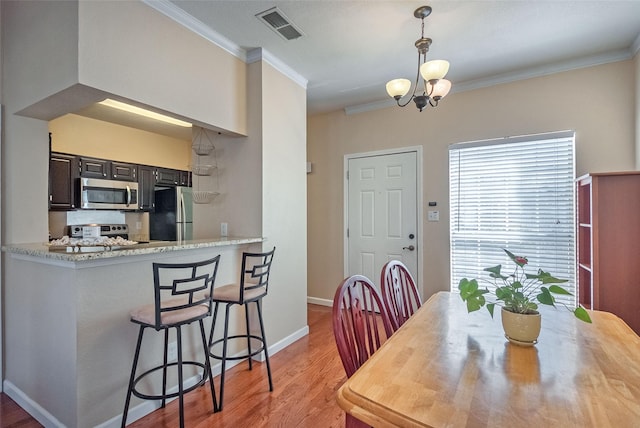 dining room featuring an inviting chandelier, crown molding, and light hardwood / wood-style flooring