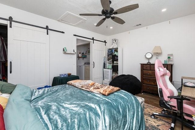 bedroom with wood-type flooring, a barn door, and ceiling fan