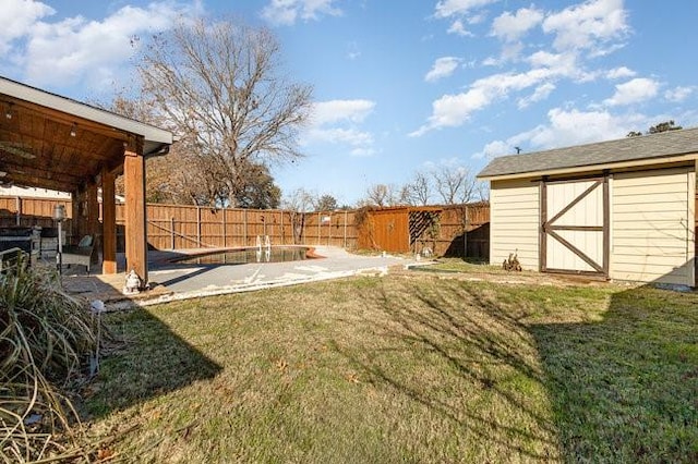 view of yard featuring a swimming pool, a patio area, and a shed