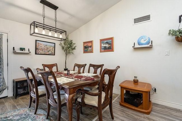 dining space with vaulted ceiling and hardwood / wood-style floors