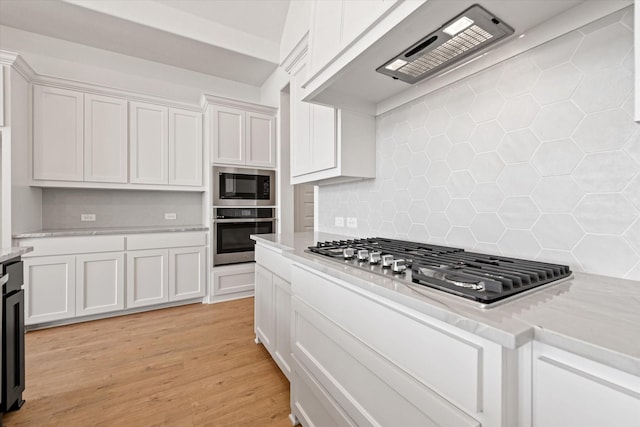 kitchen featuring light stone counters, stainless steel appliances, light hardwood / wood-style floors, backsplash, and white cabinetry