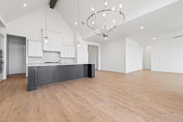 kitchen with white cabinetry, tasteful backsplash, a spacious island, high vaulted ceiling, and pendant lighting