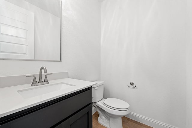 bathroom featuring toilet, vanity, and hardwood / wood-style flooring