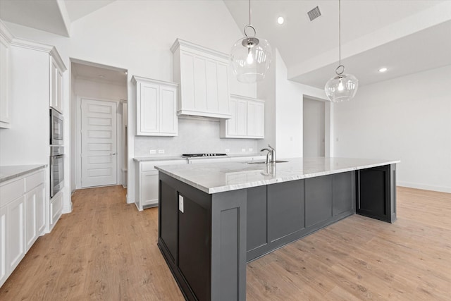 kitchen with hanging light fixtures, a spacious island, sink, white cabinetry, and tasteful backsplash