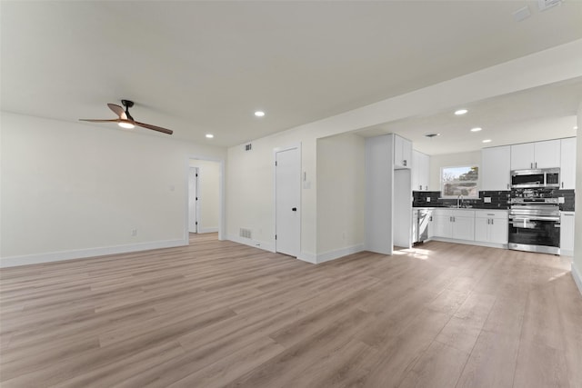 unfurnished living room with ceiling fan, light hardwood / wood-style flooring, and sink