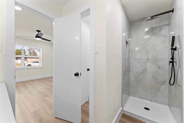 bathroom with a tile shower, wood-type flooring, and ceiling fan